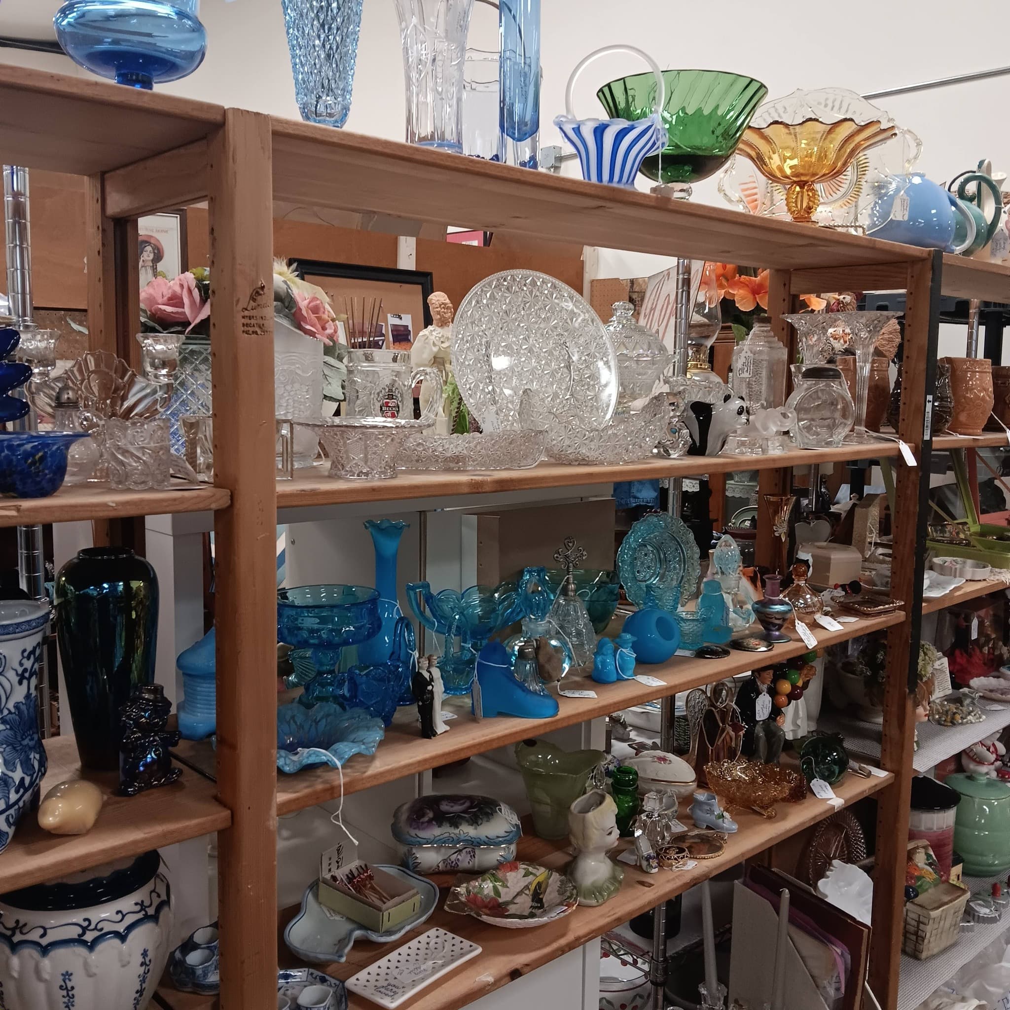 Shelves of colorful art glass including blue vases, amber bowls, and crystal pieces